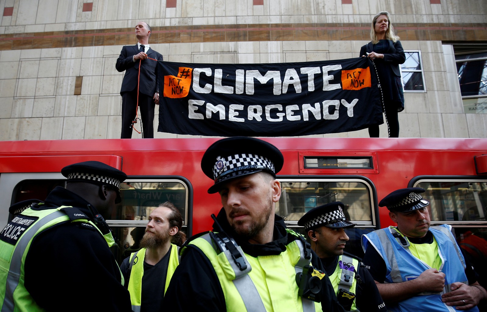 Ativistas fazem protesto contra as mudanças climáticas em uma estação de trem de Londres nesta quarta (17). — Foto: Henry Nicholls/Reuters