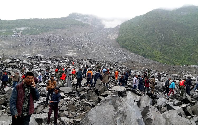 Chinese military police and rescue workers are seen at the site of a landslide in in Xinmo village, Diexi town of Maoxian county, Sichuan province on June 24, 2017. 
Around 100 people are feared buried after a landslide smashed through their village in southwest China's Sichuan Province early Saturday, local officials said, as they launched an emergency rescue operation. / AFP PHOTO / STR / China OUT / The erroneous mention[s] appearing in the metadata of this photo by STR has been modified in AFP systems in the following manner: [Maoxian] instead of [Maoxiang]. Please immediately remove the erroneous mention[s] from all your online services and delete it (them) from your servers. If you have been authorized by AFP to distribute it (them) to third parties, please ensure that the same actions are carried out by them. Failure to promptly comply with these instructions will entail liability on your part for any continued or post notification usage. Therefore we thank you very much for all your attention and prompt action. We are sorry for the inconvenience this notification may cause and remain at your disposal for any further information you may require.