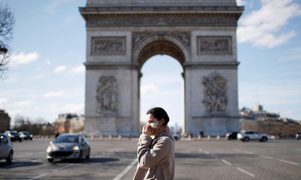 Uma mulher usando uma máscara protetora caminha perto do Arco do Triunfo enquanto a França enfrenta um surto de doença por coronavírus (COVID-19), em Paris