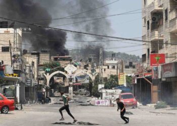 Palestinos correm durante confronto com soldados israelenses (ao fundo), em Jenin: escalada de violência na região - (crédito: Jaafar Ashtiyeh/AFP)