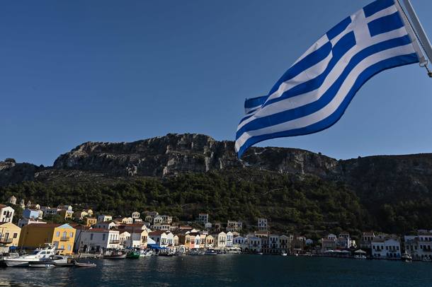 This picture shows a view of the tiny Greek island of Kastellorizo (Megisti) with a Greek flag, in the Dodecanese, the furthest south eastern Greek Island, two kilometers from the Turkish mainland, on August 28, 2020. (Photo by Louisa GOULIAMAKI / AFP)