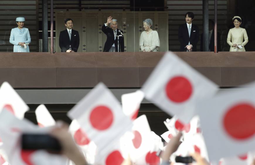 Emperor Akihito waves with members of the Imperial family from a balcony as well-wishers wave Hinomaru flags at the Imperial Palace in Tokyo on Friday to mark his 83rd birthday. | AP